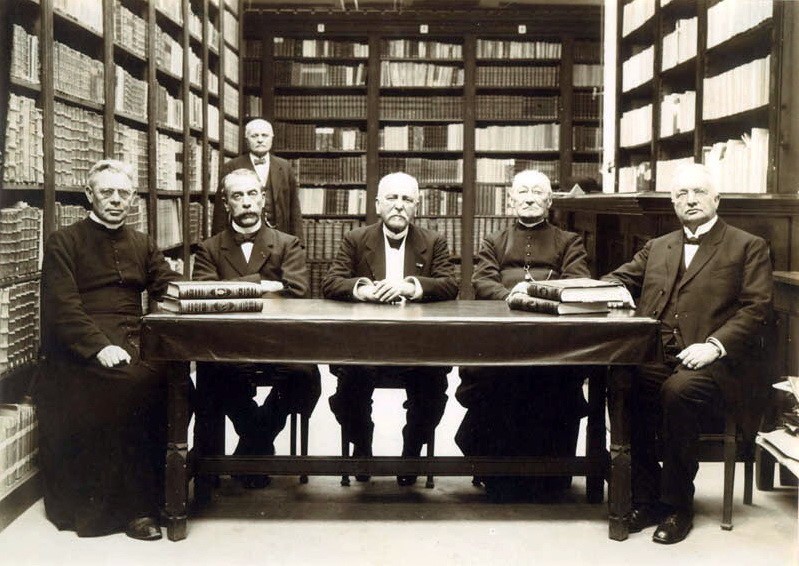 Leden van de Maastrichtse Stedelijke Monumenten Commissie ("Commissie voor de Bewaring van Geschiedkundige Gedenkstukken") poseren in het Generaalshuis (Gemeentearchief en -bibliotheek), Vrijthof 47. Eerste van links: dr. J.W.H. Goossens (gemeente-archivaris), tweede van links: dr. P.M.H. Doppler (hoofdcommies Rijksarchief). (Fotocollectie RHCL Maastricht, GAM 10426).